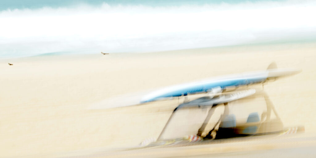 Photographie « Dream », série Songes de Sabine Chabot : Un surf sur la voiture semble sortir de nulle part au milieu de la tempête.