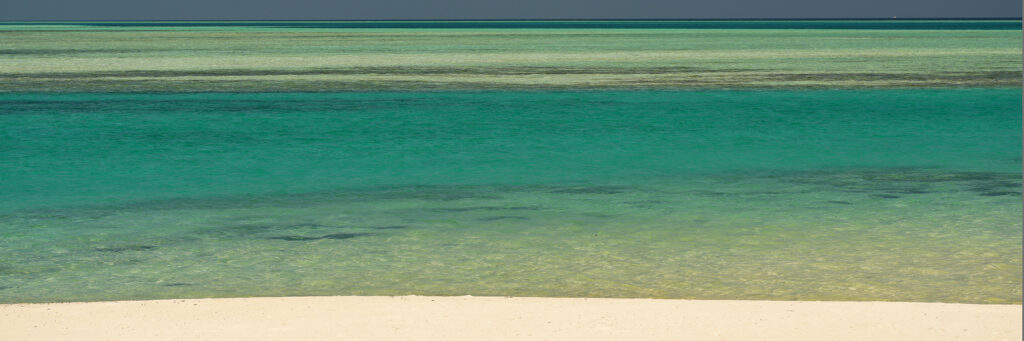 Photographie « Horizon2 », série Horizons de Sabine Chabot. Entre plage, lagon et ciel, le paysage se construit par une succession de lignes et de nuances de bleu et de vert